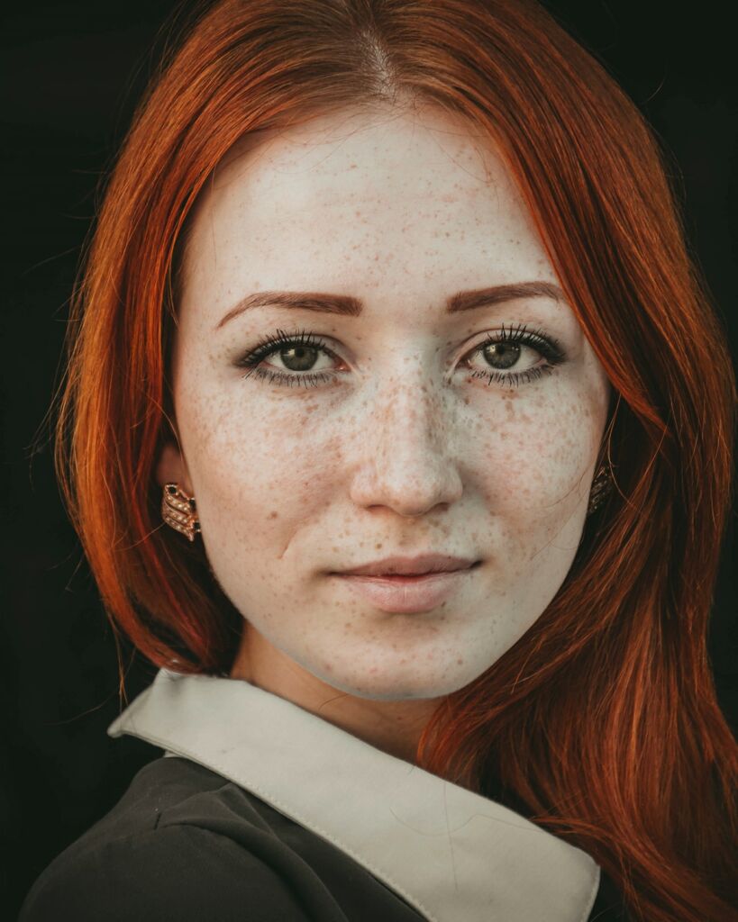A woman with red hair faces the camera.